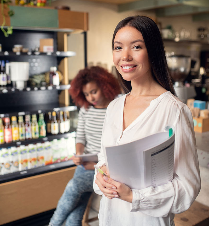 woman holding open sign and smiling because she has a business checking account with ascent bank