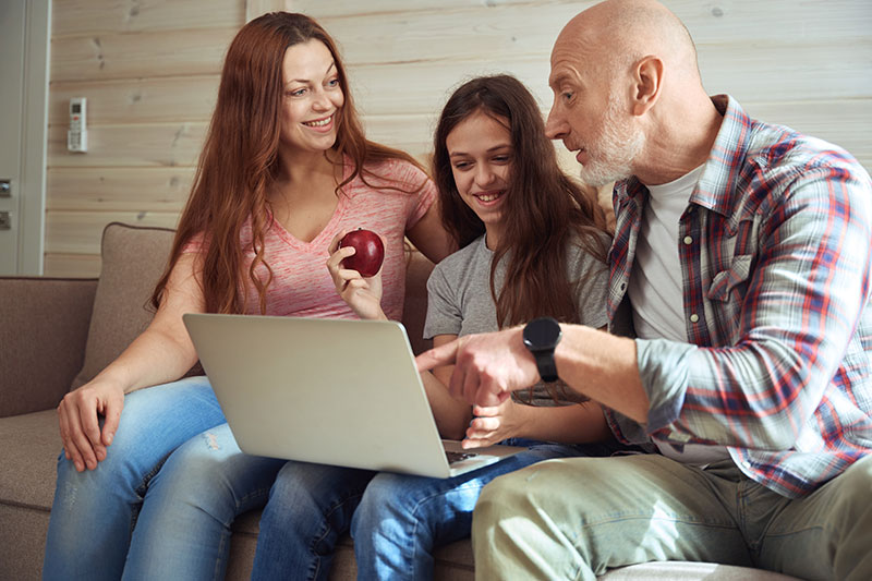 family sitting on sofa looking at laptop